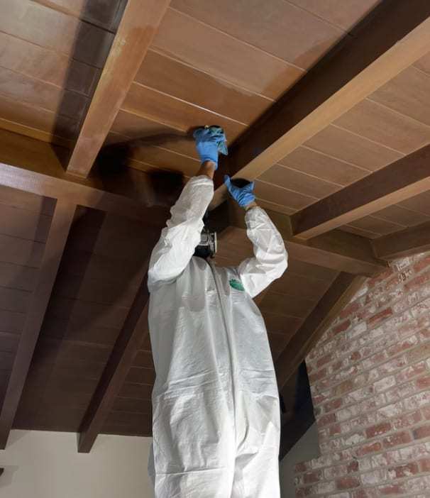 Technician in a protective suit cleaning a wood plank ceiling